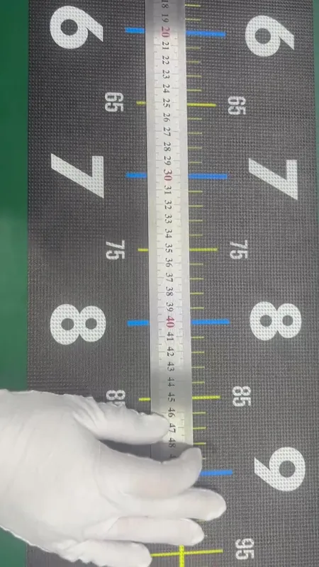 白い手袋の手が金属の定規を目盛りに当てて、長さを照合している様子
